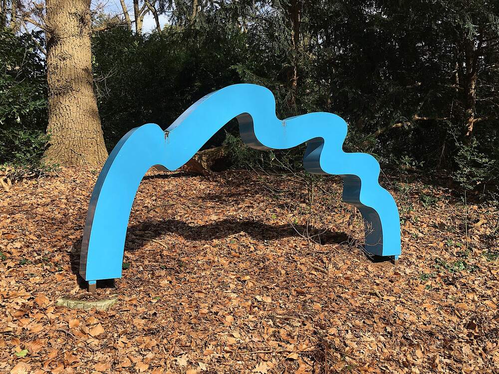 Een blauw kunstwerk tussen de herfstbladeren in beeldenpark Odapark in Venray